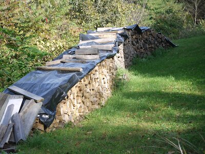 Firewood stack covered with plastic sheeting.