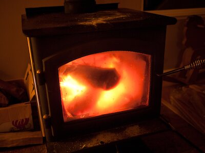 A wood stove with some firewood burning in it.
